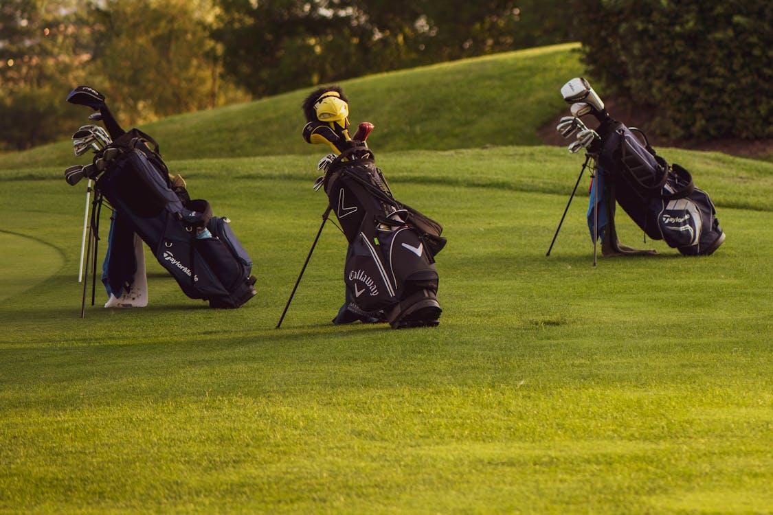 Trois sacs de golf alignés sur un parcours prêts pour une partie